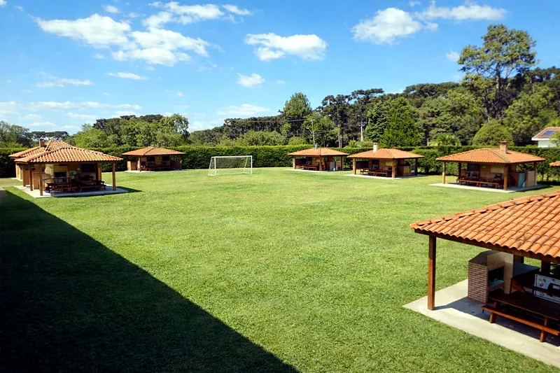 Campo gramado com os quiosques de churrasqueira ao fundo